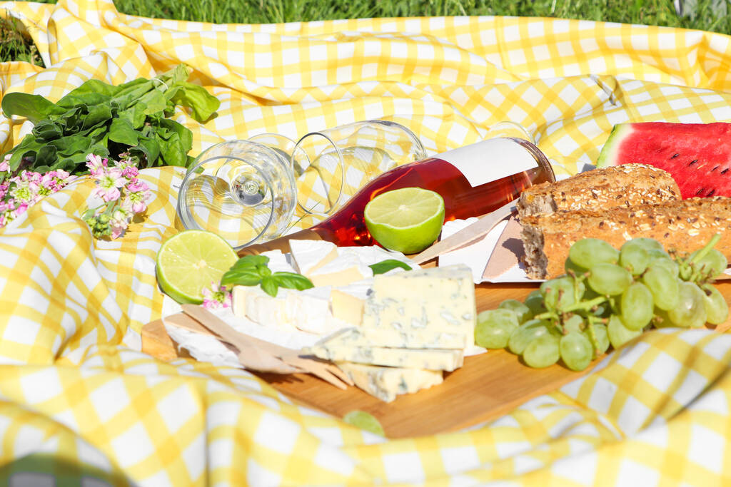 Picnic blanket with delicious food and wine outdoors on sunny day - Valokuva, kuva