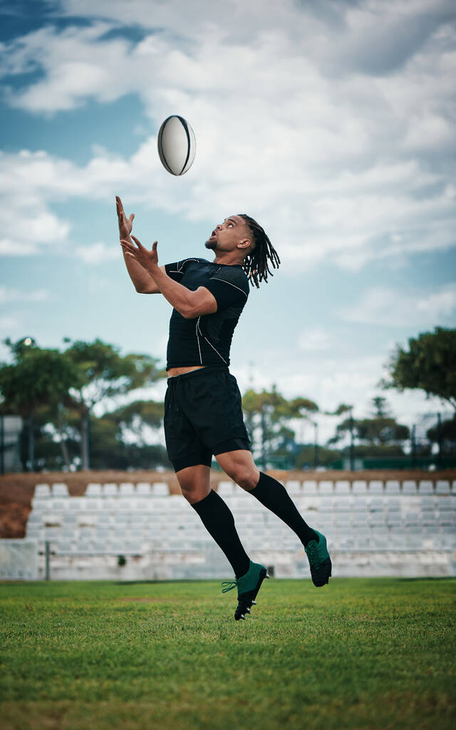 The ball is his to have. Full length shot of a handsome young rugby player catching a ball mid-air on the field - Foto, Imagen