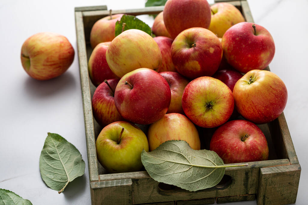 Свежие фермерские яблоки в деревянном ящике собирают фрукты на легкой поверхности домашней пищи - Фото, изображение