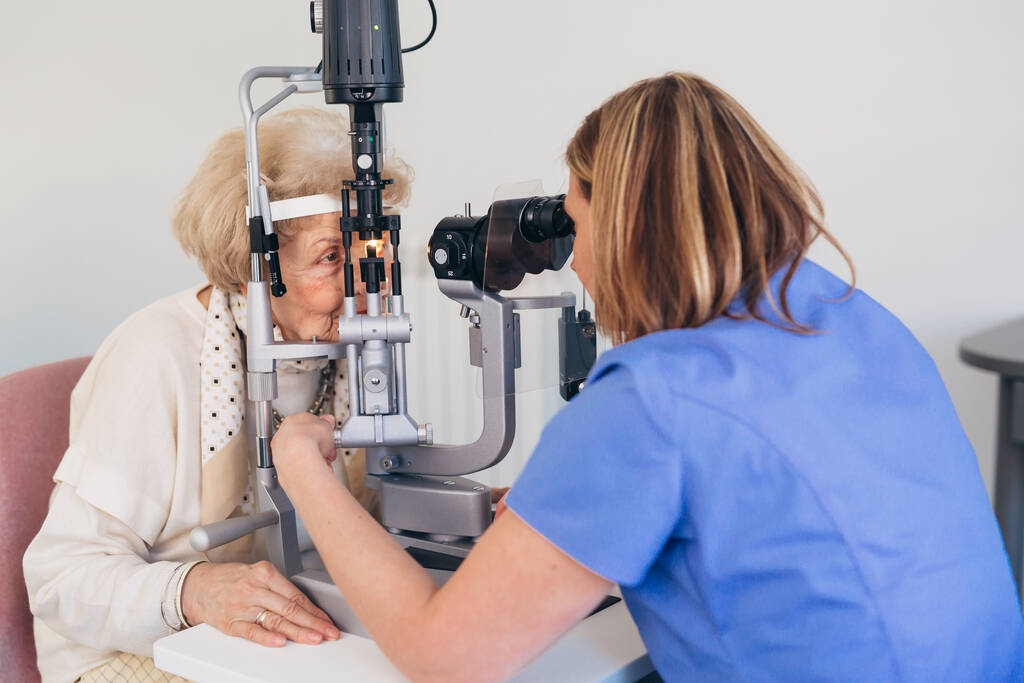 senior vrouw controleren van haar gezichtsvermogen in kliniek - Foto, afbeelding
