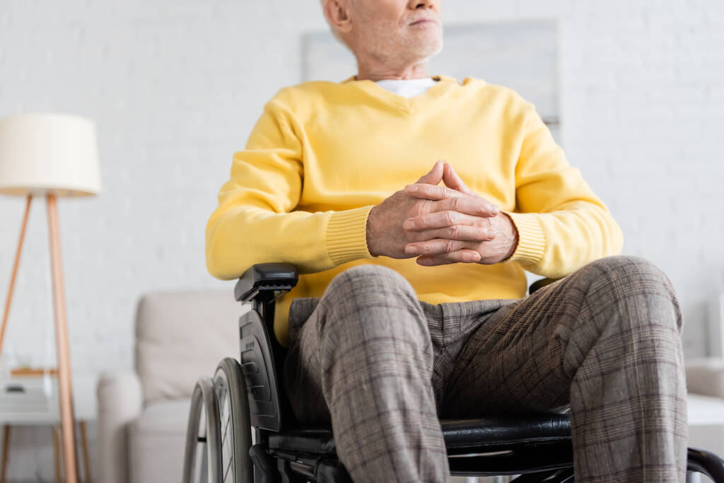 Обрезанный вид пенсионера, сидящего в инвалидной коляске дома  - Фото, изображение