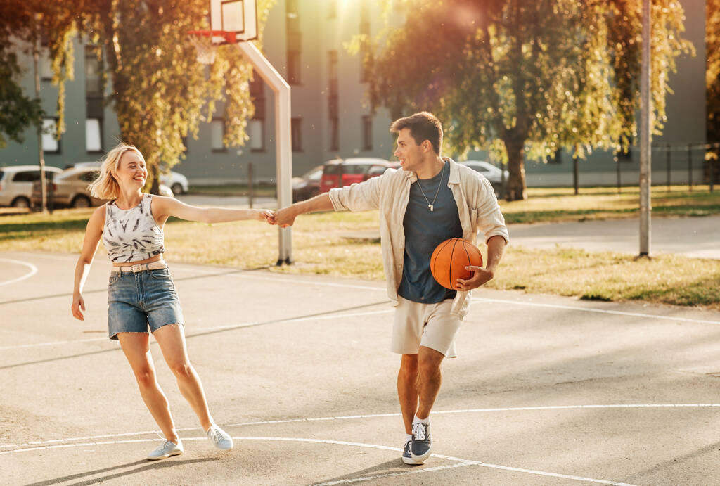 sport, amour et concept de personnes heureux jeune couple avec balle sur terrain de basket-ball - Photo, image