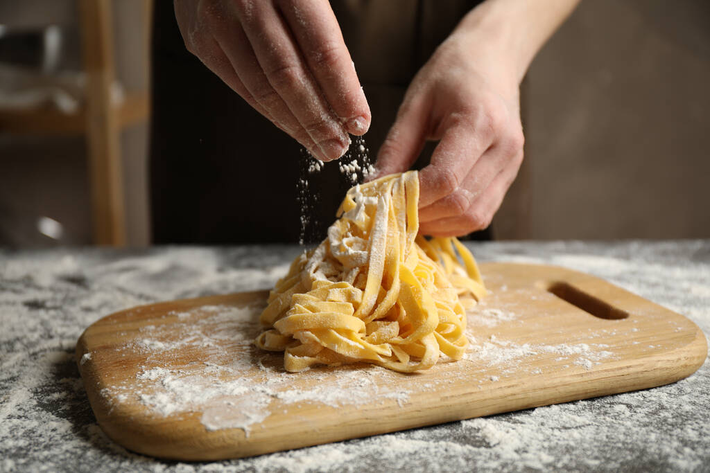 Vrouw die pasta bereidt aan tafel, close-up zicht - Foto, afbeelding