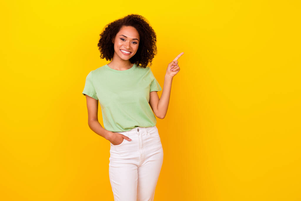 Photo of nice brunette curly lady index promo wear t-shirt pants isolated on bright yellow color background. - Fotó, kép