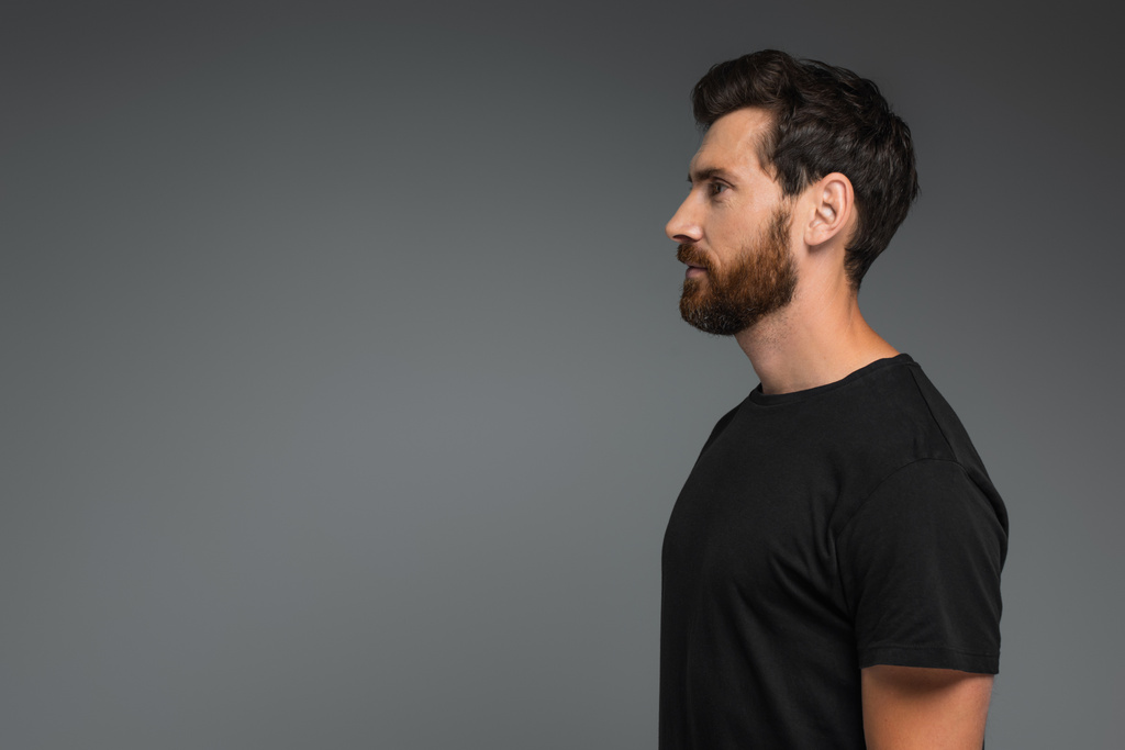 вид збоку бородатого чоловіка в чорній футболці, який дивиться ізольовано на сірому
 - Фото, зображення