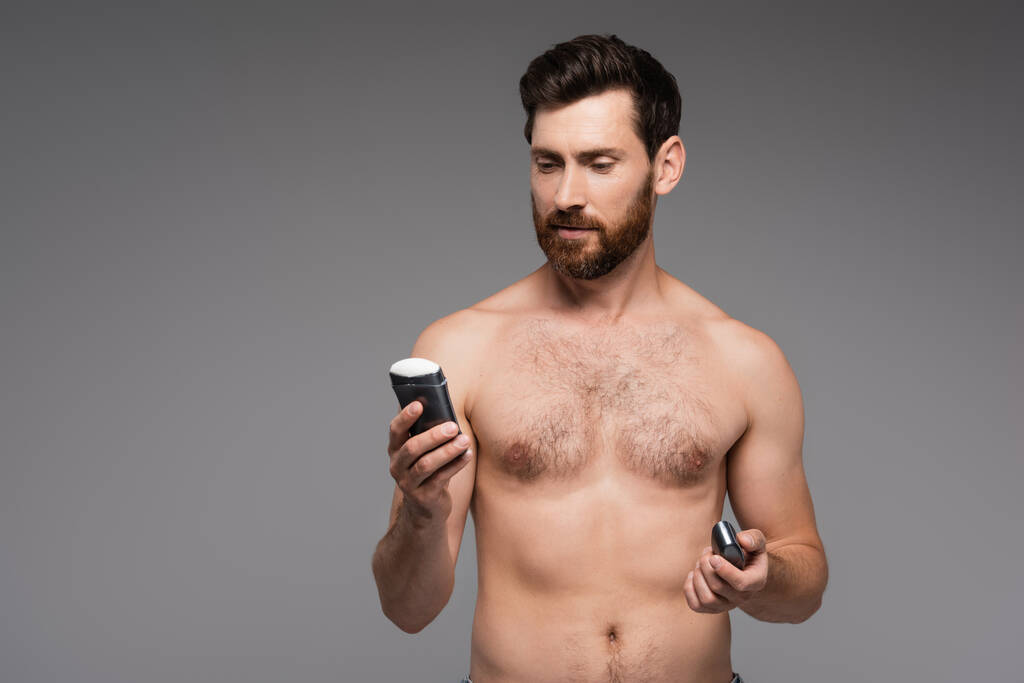 shirtless man with beard holding solid stick deodorant isolated on grey - Foto, Imagem