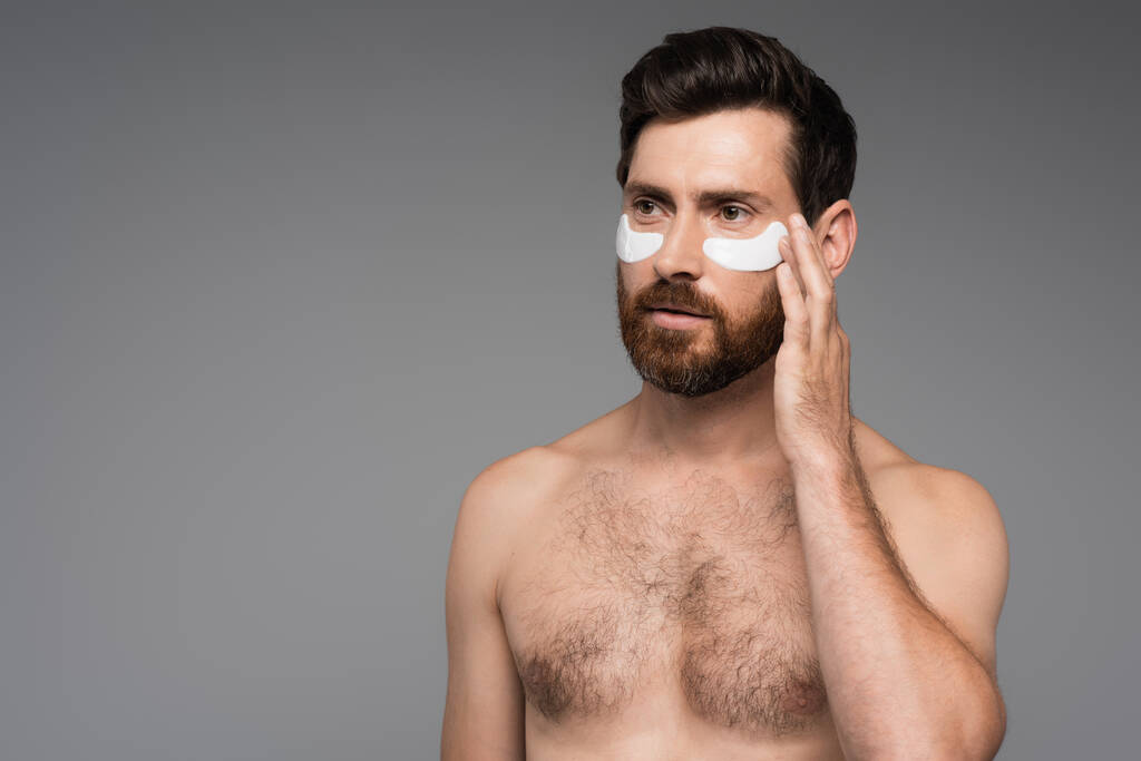 shirtless and bearded man with moisturizing eye patches isolated on grey  - Foto, Imagen