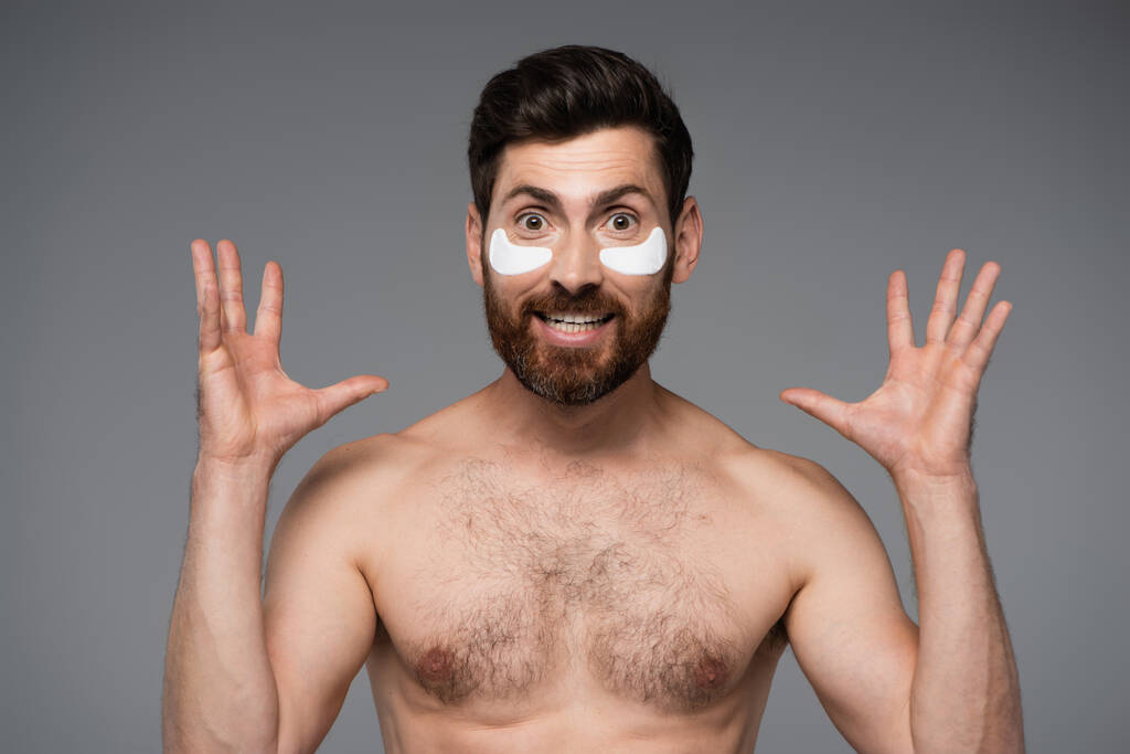 збуджений бородатий чоловік зі зволожуючими очними латками, що жестикулюють ізольовано на сірому
  - Фото, зображення