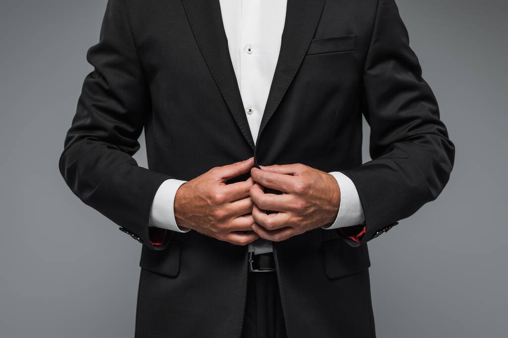 cropped view of elegant man in black tuxedo adjusting blazer isolated on grey - Foto, Imagem
