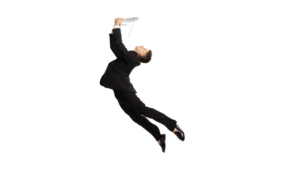 Reading contract. Young office worker in business suit jumping with papers isolated over white background. Motivation, strategy, psychology, business, job concept. copyspace for ad - 写真・画像