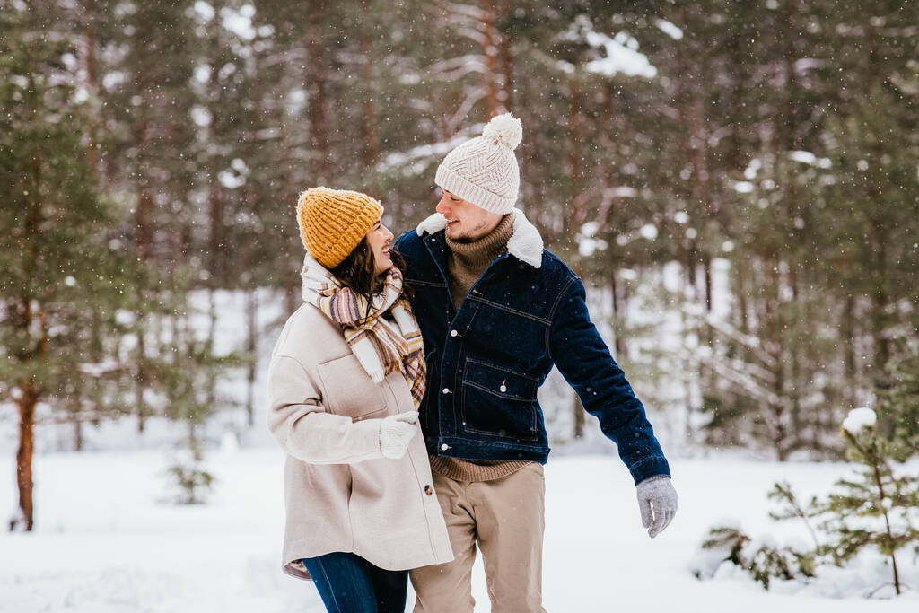 emberek, szerelem és szabadidő koncepció - boldog mosolygós pár sétál a téli erdőben - Fotó, kép