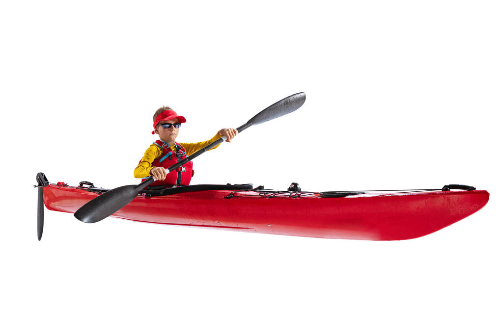 Kids and sport. Beginner kayaker in red canoe, kayak with a life vest and a paddle isolated on white background. Concept of sport, nature, travel, active lifestyle. Copy space for ad, text, design - Foto, immagini