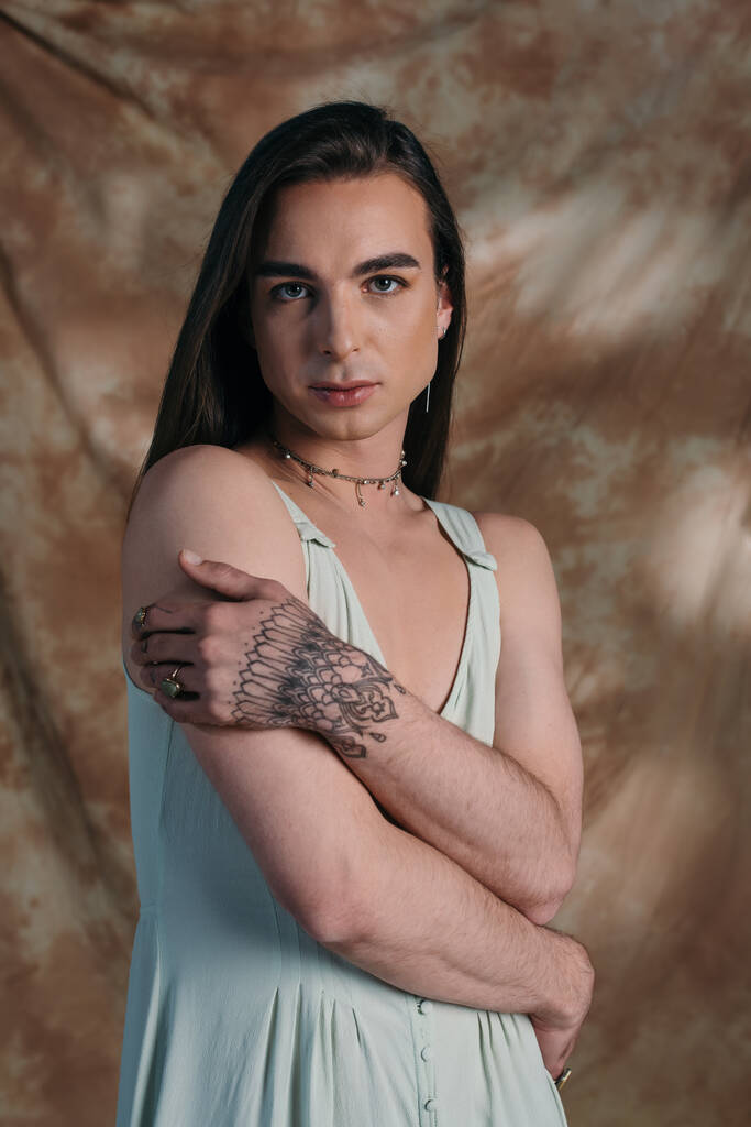 Portrait of brunette queer person in sundress looking at camera on abstract background  - Foto, immagini