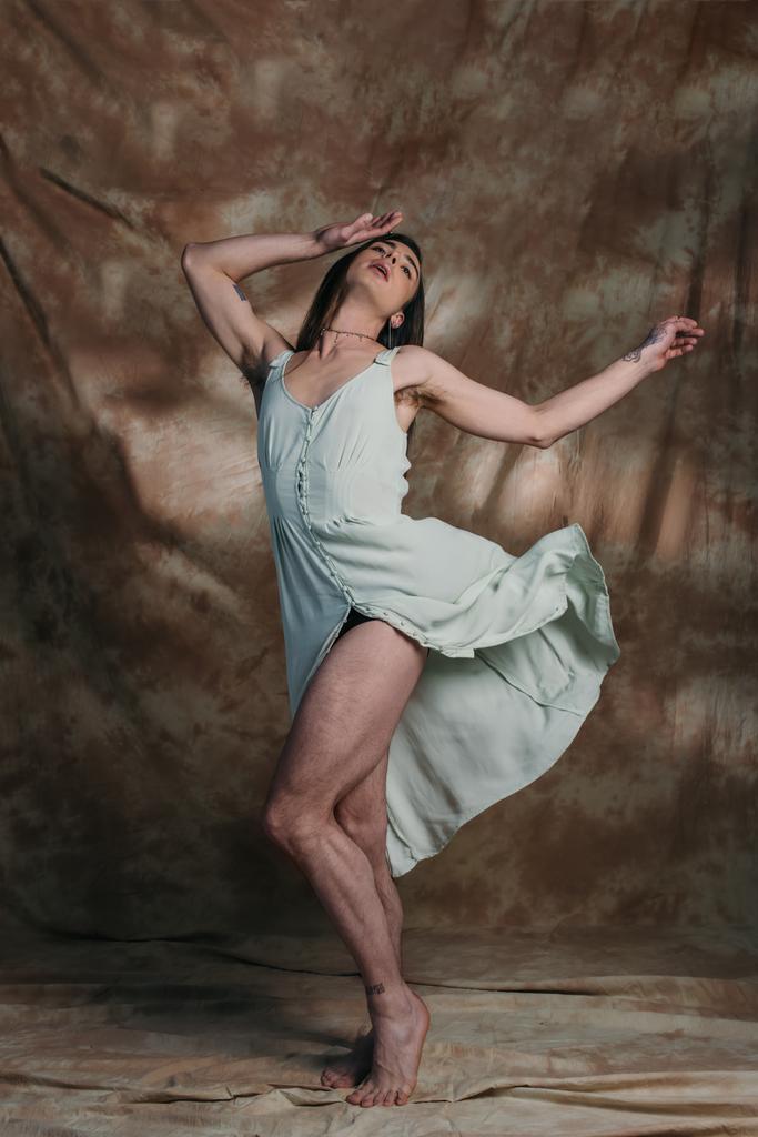 Stylish queer person in sundress posing on abstract brown background  - Fotografie, Obrázek