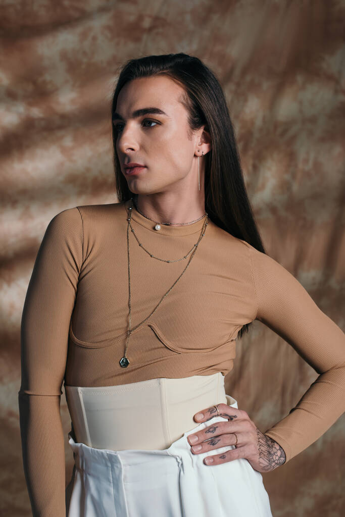 Queer person in corset posing and looking away on abstract brown background  - Photo, image