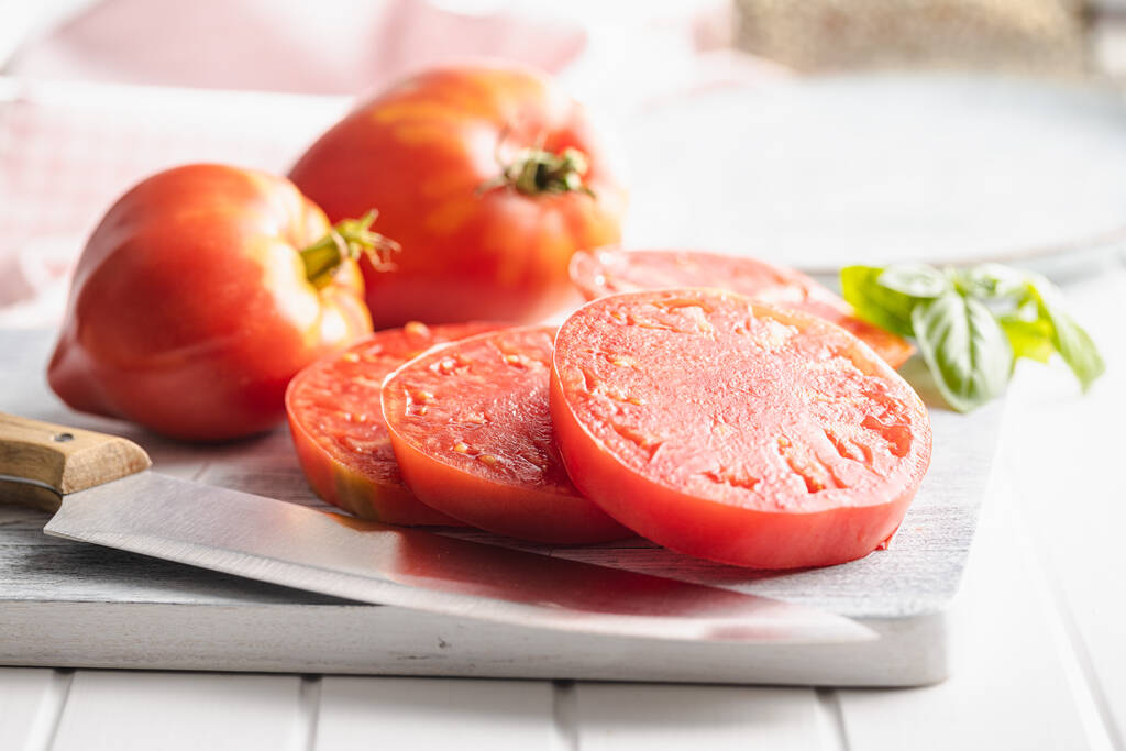 Sliced bull heart tomatoes on a cutting board. - Fotó, kép