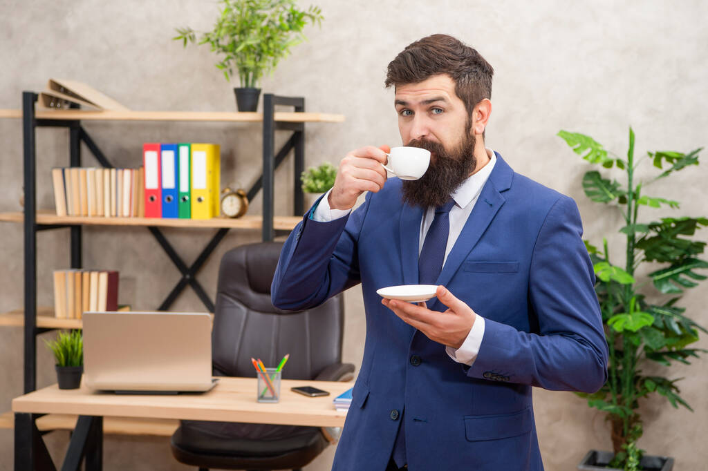 позитивний зрілий підприємець в куртці має кавову перерву в офісі, вранці
. - Фото, зображення