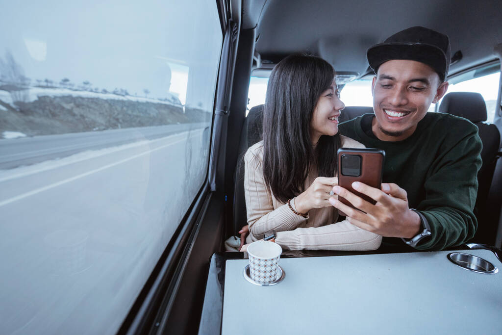 азіатська пара використовує смартфон разом під час подорожі на машині, сидячи біля вікна
 - Фото, зображення