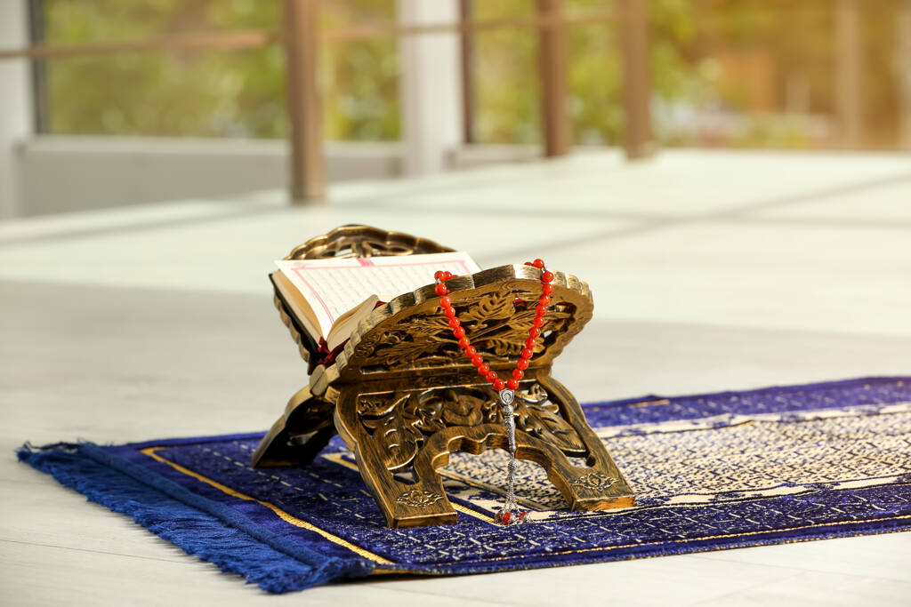 Rehal with open Quran and Misbaha on Muslim prayer rug indoors - 写真・画像