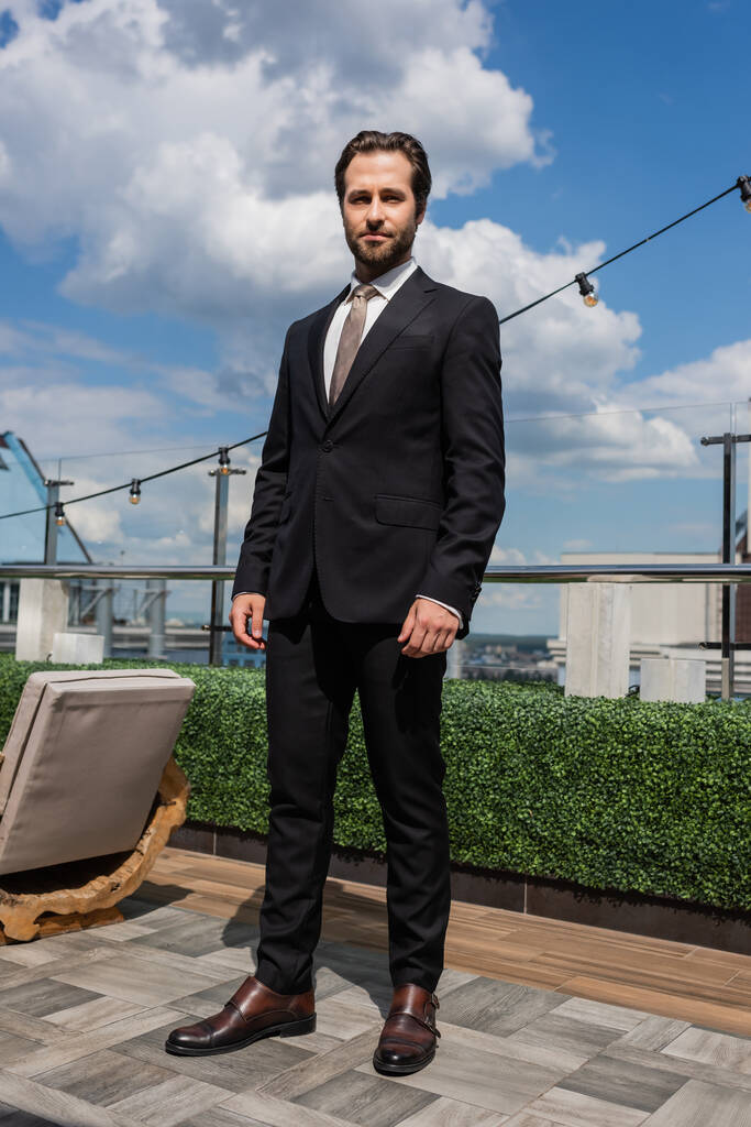 Stylish groom in suit looking at camera on terrace  - Fotoğraf, Görsel