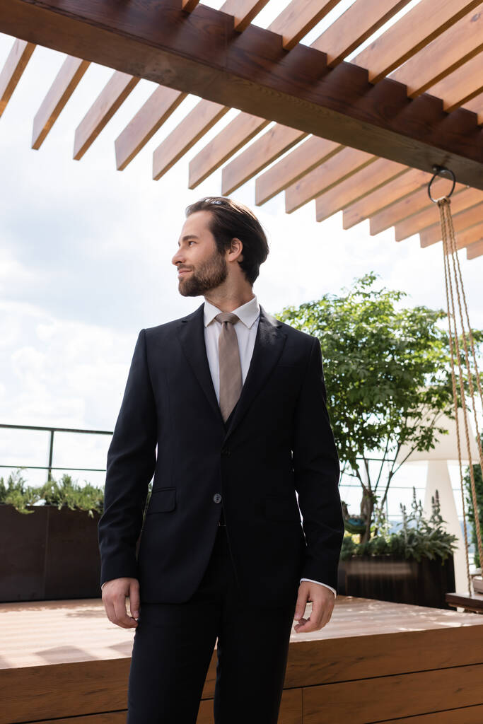 Side view of brunette groom looking away on terrace outdoors  - Photo, Image