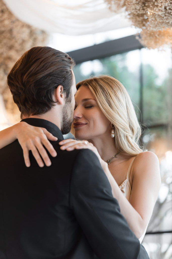 Blonde woman hugging boyfriend in suit in restaurant  - Foto, Imagem