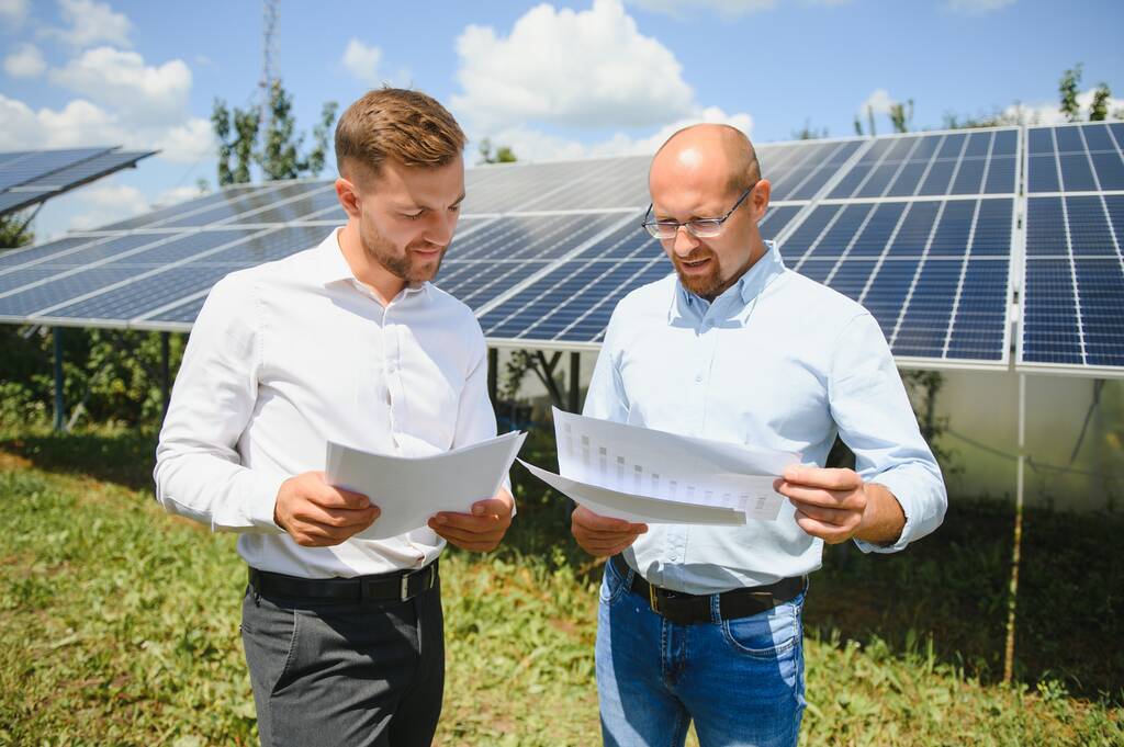 Two engineers are conducting outdoor inspection of solar photovoltaic panels. - Photo, Image