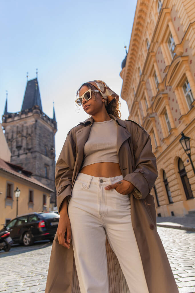low angle view of african american woman posing near old town hall tower in prague - Foto, Imagen