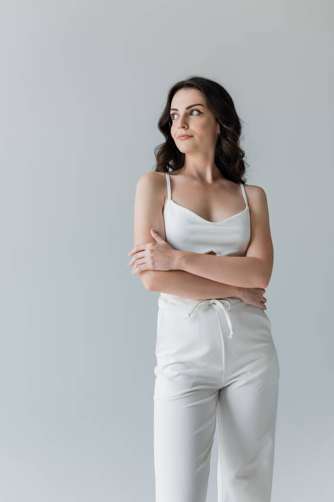 Молодая женщина в белой одежде смотрит в сторону, изолированная от серых  - Фото, изображение