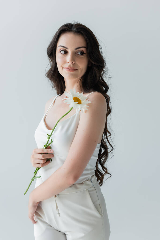 Young woman holding chamomile and looking away isolated on grey  - Foto, Bild