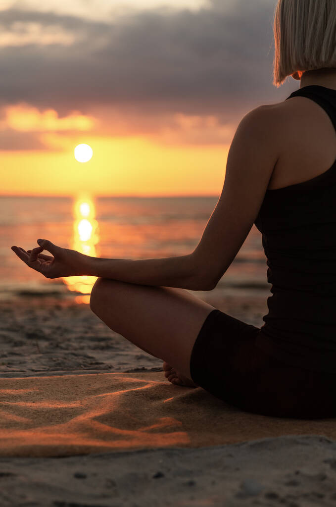 yoga, mindfulness y concepto de meditación - mujer meditando en la pose de loto en la playa al atardecer - Foto, imagen