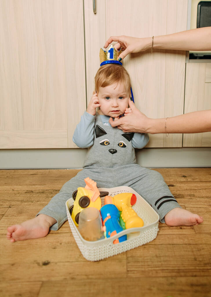 παιδί κάθεται μέσα στο πάτωμα η κουζίνα παίζει με το φωτεινό παιχνίδι - Φωτογραφία, εικόνα