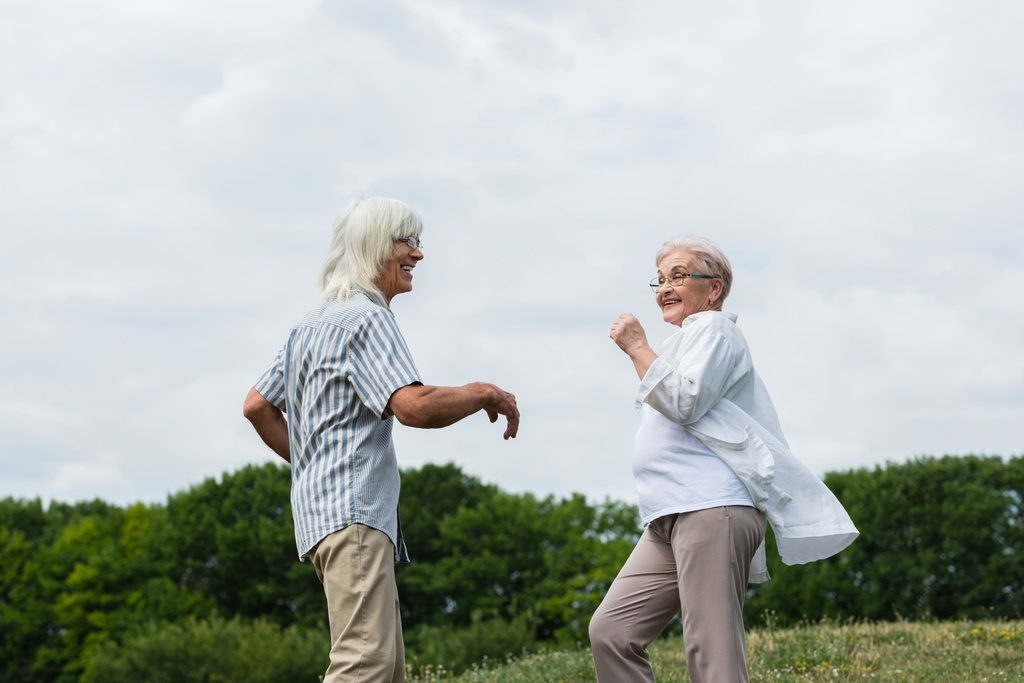 щаслива пара на пенсії в окулярах танцює і посміхається зовні
  - Фото, зображення