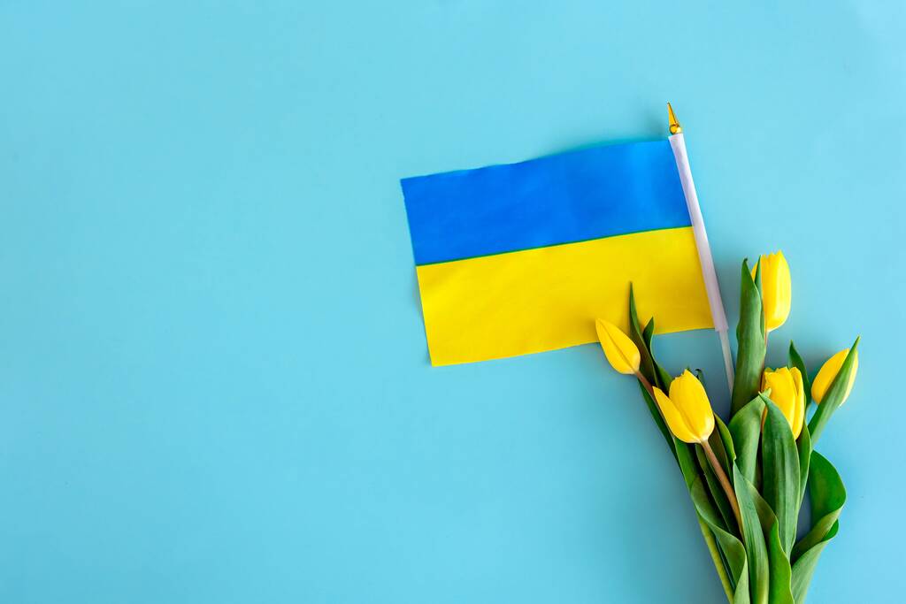 Una composición plana con flores amarillas, y la bandera de Ucrania. - Foto, imagen