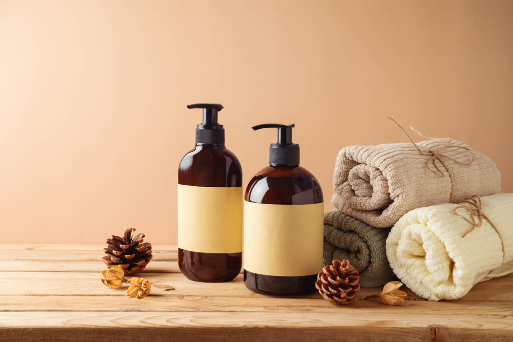 Natural beauty SPA cosmetics bottles with labels and towels for mock up packaging design on wooden table over beige background. - Foto, Imagen