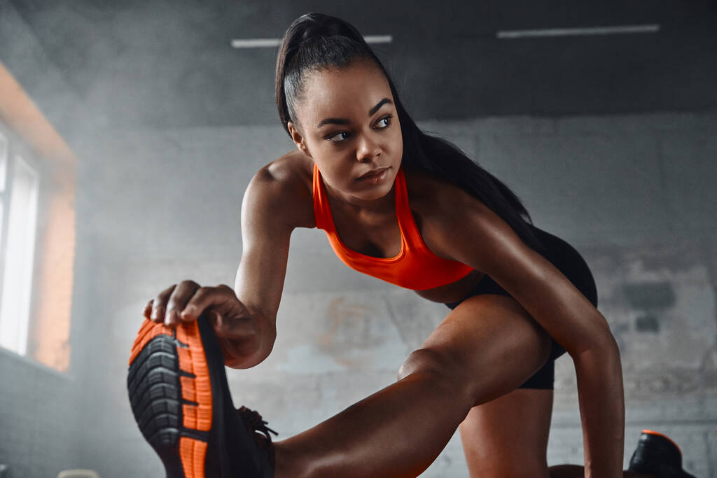 Attractive young African woman doing stretching exercises in gym - Fotoğraf, Görsel