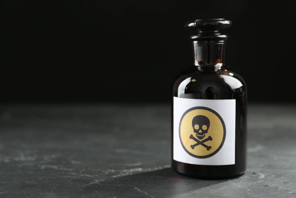 Garrafa de vidro de veneno com sinal de aviso na mesa preta. Espaço para texto - Foto, Imagem