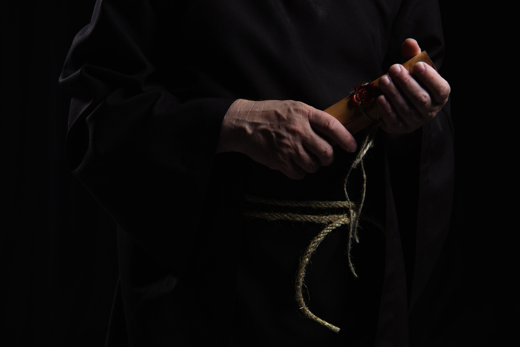 vista parziale dell'abate che tiene il manoscritto arrotolato con sigillo di cera isolato su nero - Foto, immagini