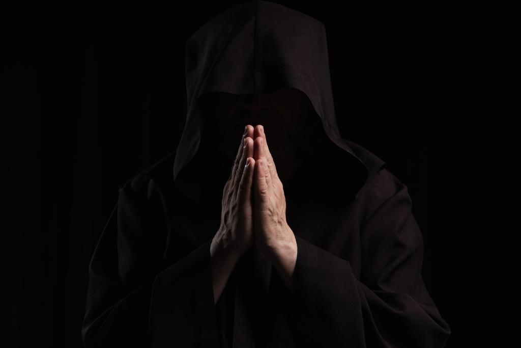 vista frontale di misterioso monaco anonimo con le mani in preghiera isolate sul nero - Foto, immagini
