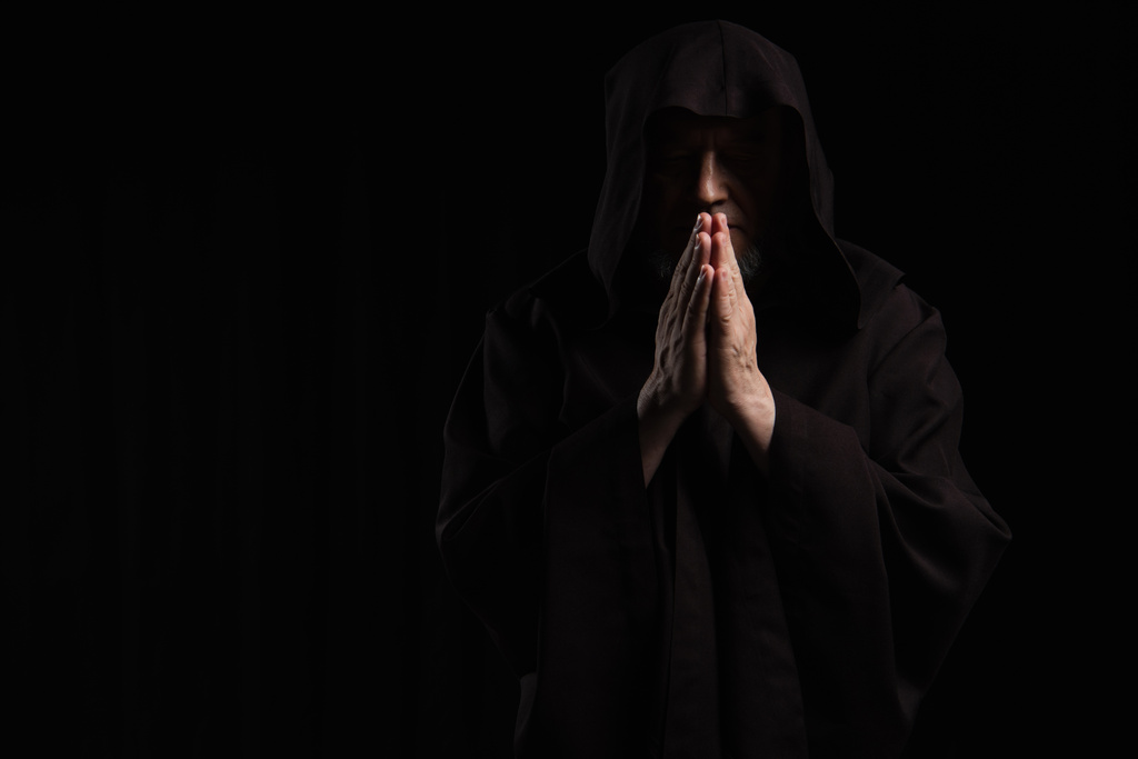 přední pohled na tajemného mnicha v kápi sutaně modlí izolované na černé - Fotografie, Obrázek