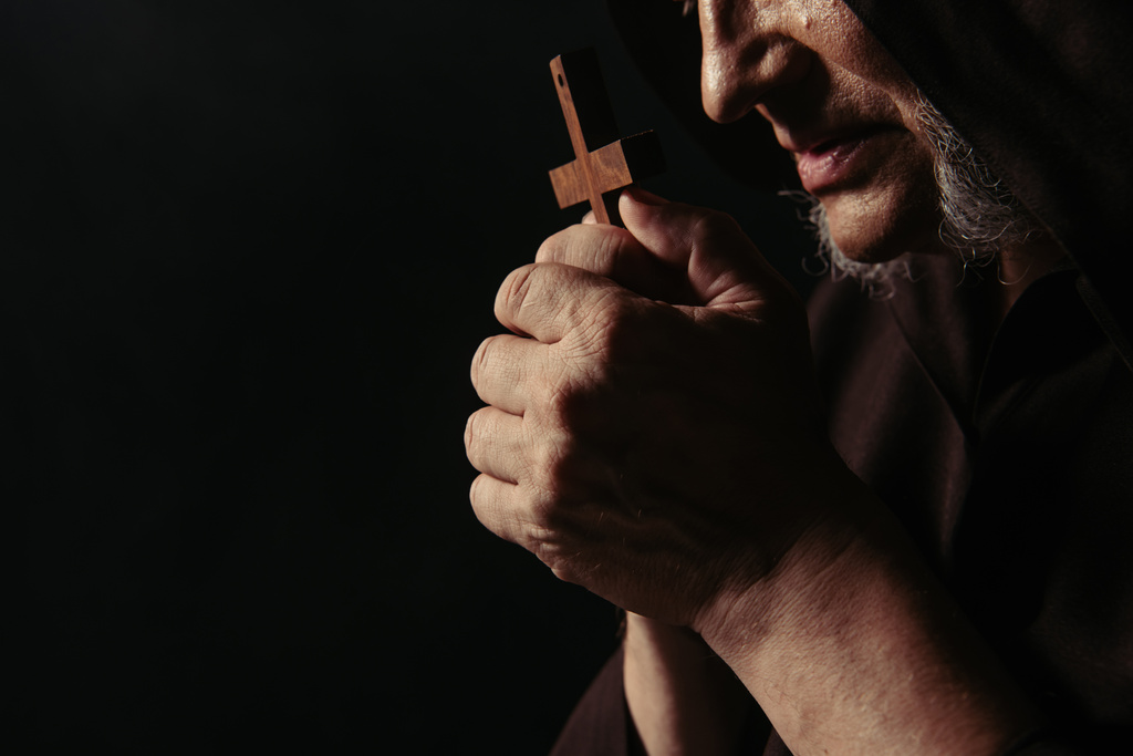 przycięty widok średniowiecznego mnicha modlącego się z krzyżem odizolowanym na czarno - Zdjęcie, obraz