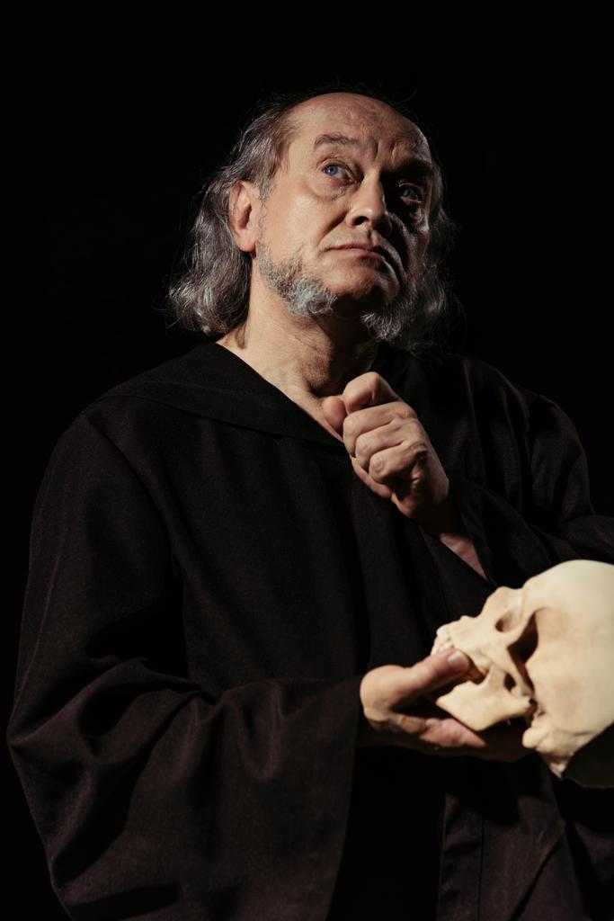 średniowieczny filozof religijny z czaszką patrząc w górę, myśląc odizolowany na czarno - Zdjęcie, obraz