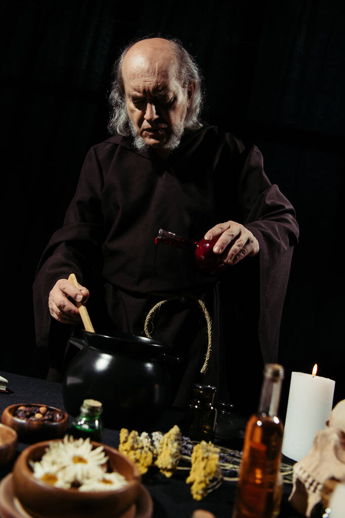 vezető alkimista hozzá folyadék főzés közben bájital éjjel elszigetelt fekete - Fotó, kép