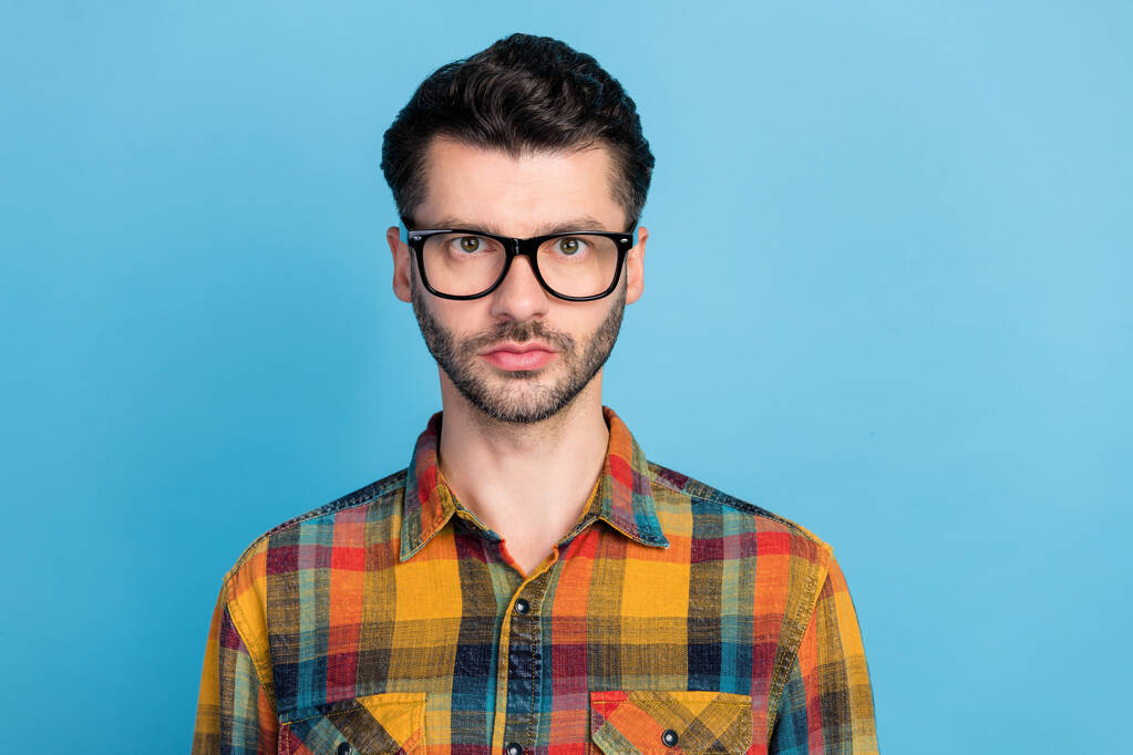 Photo of young handsome bearded man in eyeglasses dressed checkered shirt standing look at camera isolated on blue color background. - Fotoğraf, Görsel