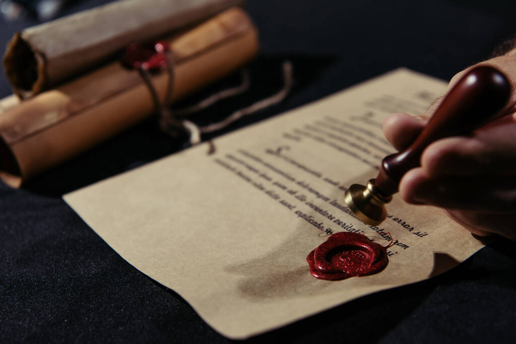 cropped view of blurred monk holding wax seal near manuscript and rolled parchments - Photo, Image