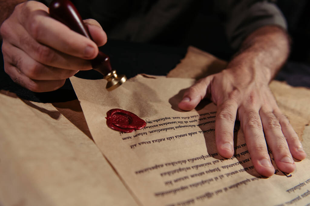 partial view of abbot approving ancient manuscript with wax seal on black background - Photo, Image