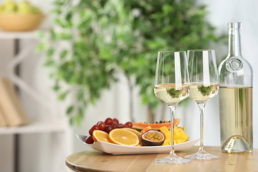 Herkullisia eksoottisia hedelmiä ja viiniä puupöydällä sisätiloissa, tilaa tekstille - Valokuva, kuva
