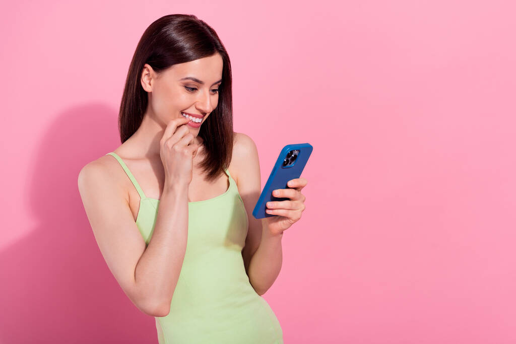 Photo of pretty tricky young lady wear green dress typing modern device empty space isolated pink color background. - 写真・画像