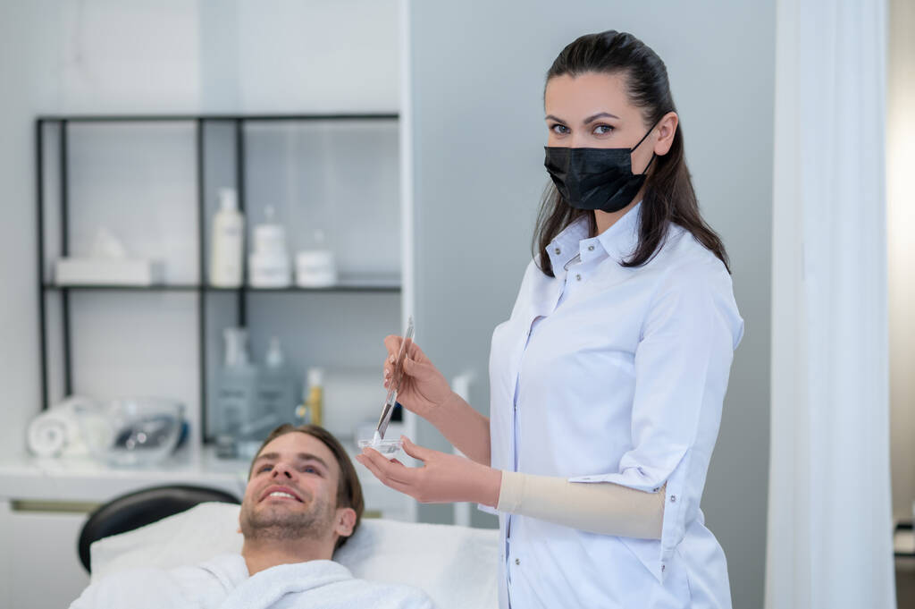 Beauty salon. Cosmetologist applying facial mask to mans face - Photo, Image