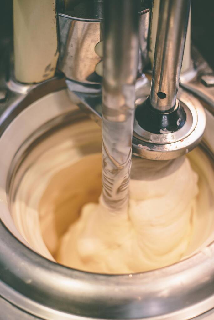 Un primo piano di un processo di fabbricazione del gelato italiano con una crema bianca - Foto, immagini
